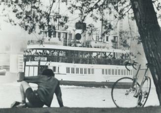 Cyclist sits, watches as ferry William Inglis slides on her way, carrying visitors from the hustle of the city to the quiet and peace of the car-less (...)