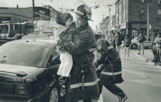 To the rescue, Toronto firefighter Michael Barrington, of Station 14, holds a youngster involved in a collison at Gladstone Ave. and Dundas St. around noon yesterday