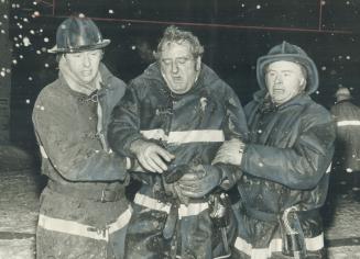 Aid to a buddy in distress, Fireman Bill Bennett of number 8 Station is helped to ambulance by firefighter Bill Cameron (left) and Trevor Harris durin(...)
