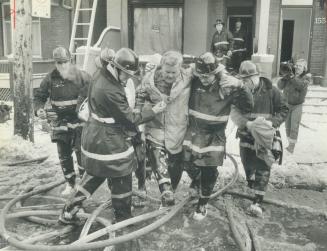 Fire victim, Toronto platoon chief Jack Smith is helped from a burning house on Gerrard St