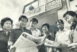 Businessmen and other Toronto Koreans gather around copies of their community newspaper, the bi-weekly Canada News