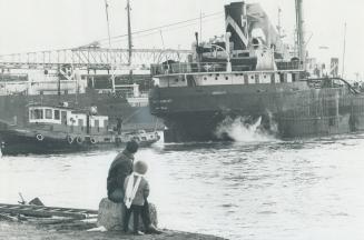 Image shows a man and his three year old son watching ships at the Harbour.