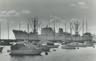 Image shows a number of small boats and one huge ship behind them on the lake.