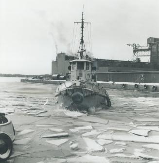 Image shows tugboat passing through the icy lake.