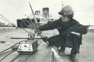 Image shows a Harbour worker with a ship in the background.