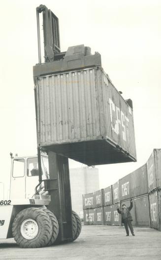 Image shows a few workers loading containers.