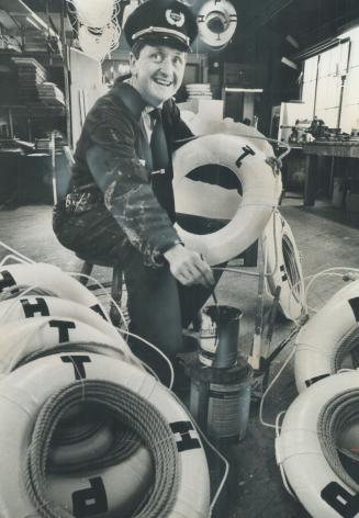 Image shows a police officer painting some letters on the life rings.