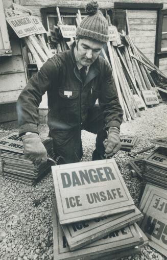 Image shows a worker preparing signs that read: "Danger Ice Unsafe".
