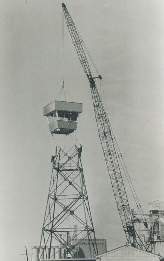 Image shows the crane uploading the top part of the police lookout station.
