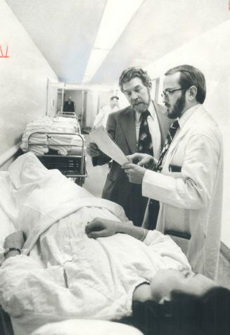 Volunteer Herbert Field is seen in East General's emergency ward, where he is about to take over with a patient after a briefing by Dr. Robert Davey. (...)