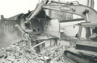 A pile of rubble and dust surround a Romano demolition crane; beyond is the gutted interior of  ...