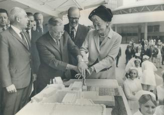 Hospital drive opens. East York Mayor True Davidson and Metro Chairman Albert Campbell take first cut in Metro's hospital cake as Mayor William Dennison looks on