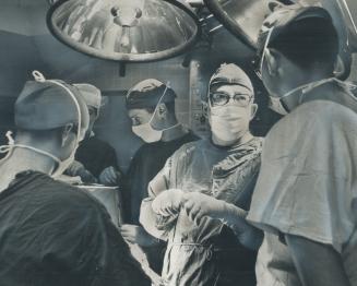 Neurosurgeon Bruce Hendrick (wearing glasses) moves to the operating table at Sick Children's Hospital