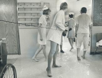 Barefoot nurses and an intern slosh through the water on the floor of the emergency wing of Wellesley Hospital today as they pass a barefoot nurse ans(...)