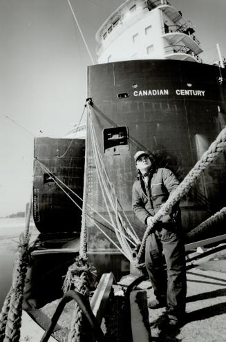 Image shows a maintenance man holding the lines with a ship behind him.