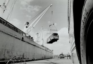 Image shows a bus being loaded on a big ship.