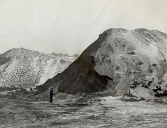 Image shows a person standing in front of the mountain of coal.