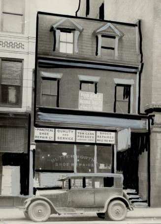 Exterior view of three-storey brick building with For Sale sign mounted above shop window. Sign ...