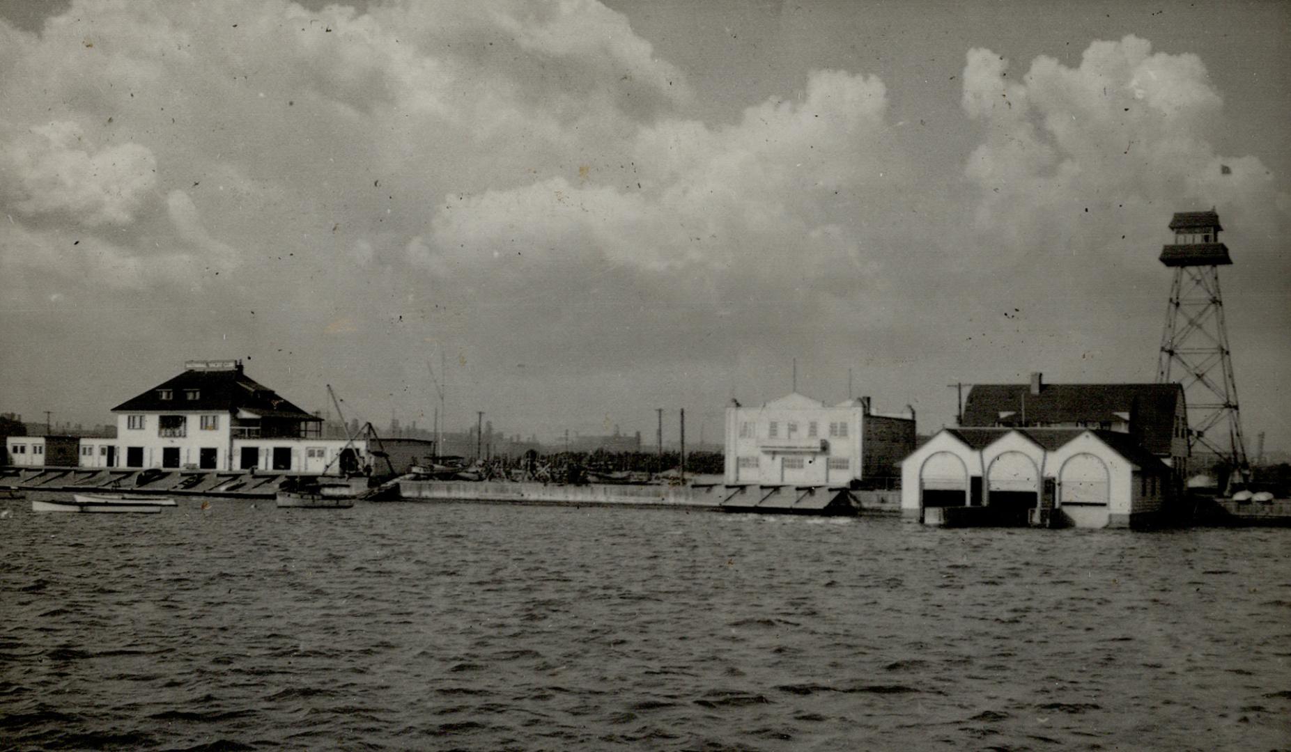Image shows a lake view with a few buildings in the background. 