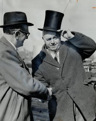 Image shows two gentlemen. One of them is trying on a hat.