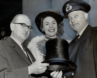 Image shows one lady and two gentlemen holding a silk hat.
