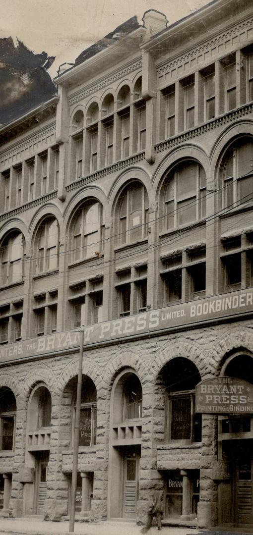 Three-story brick and stone building with arched windows displaying the sign Bryant Press Limit…