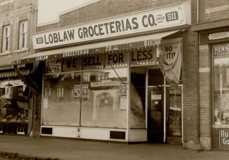 Storefront with awning. Sign in window reads, Self Serve, We Sell For Less. Sign above window r…