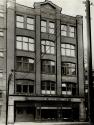 Façade of five-storey brick building. Sign above first floor windows reads, Metropolitan Motors ...
