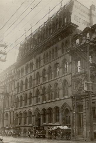 Exterior view of five-storey brick building with lancet windows. Visible portion of sign on sid…