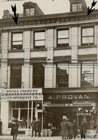 Three-story brick building with two storefronts at ground level. Left storefront sign reads, Un…