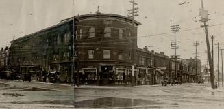 Street view of three-storey brick building at intersection with curved front. Left, sign overha…