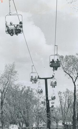Trying the skyride, one of the new features of amusement park at Centre Island, Metro Chairman William Allen (on left in front aerial car) soared 40 f(...)