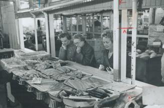 Women shopers at St. Lawrence Market. They realize fish is a budget wise buy for family