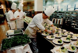 Executive chef George McNeill checks with sous-chefs as they prepare 500 appetizers for a dinner banquet