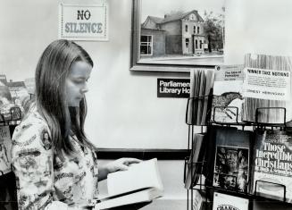Ignoring sign which discourages silence in Parliament Street Library House, Nancy Craig quietly scans a book