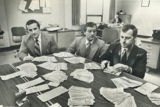 Sgt. John Cullen, crown attorney Norman Matusiak and Sgt. Jim Jones with $244,000 on the table