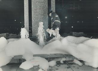 Fireman Sid Smart kicks at detergent suds engulfing the Robert Saunders Memorial Fountain on University Ave