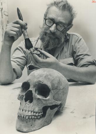 Professor Walter Kenyon. Brushing dirt off part of old skull