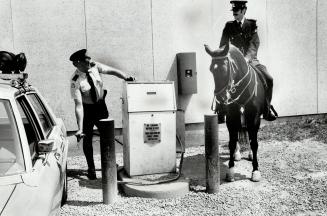 Watching Constable Paul Dewsnap gas up his patrol car, Constable James Barger and his mare, Joan, prove that horses are more fuel-efficient than autos