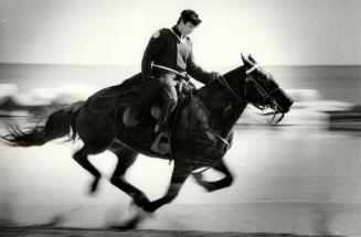 A dashingly handsome sight. A member of the metro police mounted unit pulls out all the stops and lets his horse go for a good run on Sunnyside Beach (...)