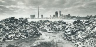 Image shows a scrap metal yard with the Toronto skyline in the background.