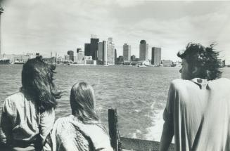 Image shows a few people on the boat with the Toronto skyline in the background.