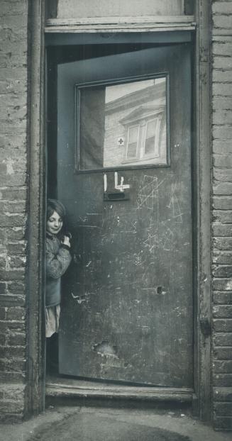 Caroll Trout, 10, peeks from behind battered door