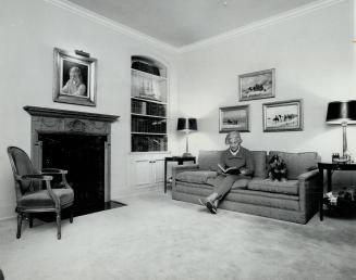 Mrs. Winnett relaxes in her library. The fireplace is an Adam replica from England and three originals by Cornelius Kreighoff hang on the wall. The po(...)
