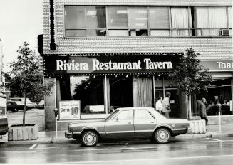Black sign with white letters above large picture window, reads, Riviera Restaurant Tavern; sig ...