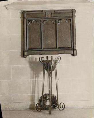 Bronze wall-mounted plaque with three inset panels with lists of names.