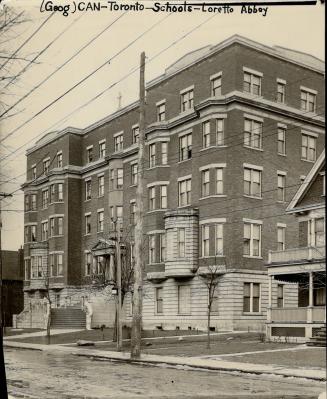 Street view of five-storey flat roofed brick building with double-hung windows and stone steps …