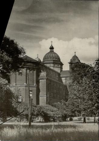 View through trees of Abbey, showing pillars half way up octagonal portion of structure in fore…
