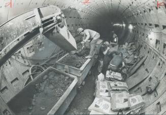 With pneumatic spades roaring, miners chisel out the twin 1,960-foot-long tunnels for the Spadina rapid transit line at rate of 12 feet a day. Schedul(...)