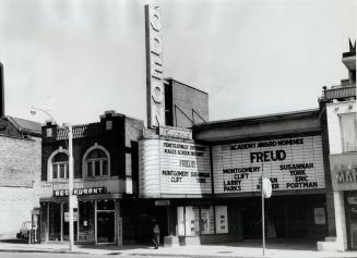 Image shows the front of the movie theatre entrance with some advertising boards.
